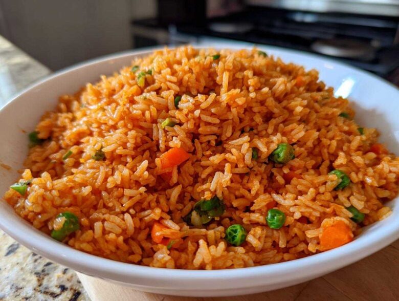 Close-up of a white bowl filled with vibrant orange spanish rice mixed with peas and carrots.