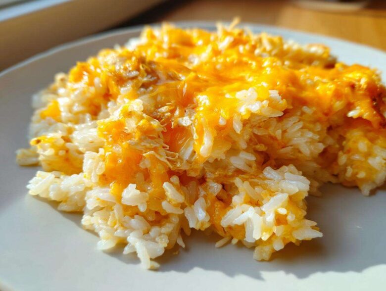 Close-up of a serving of fluffy white rice topped with melted, bright orange cheddar cheese, highlighting the cheesy rice texture.