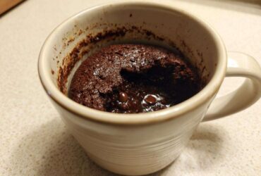 Close-up of a rich, fudgy chocolate mug cake with melted chocolate chips inside, ready to eat.