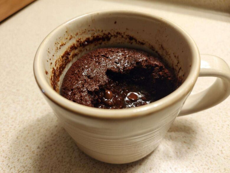 Close-up of a rich, fudgy chocolate mug cake with melted chocolate chips inside, ready to eat.