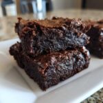 Close-up of rich, fudgy sweet potato brownies stacked on a white plate.