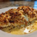 Close-up of a perfectly baked Garlic Parmesan Chicken Bake with a crispy golden crust, sitting in a pool of buttery sauce.