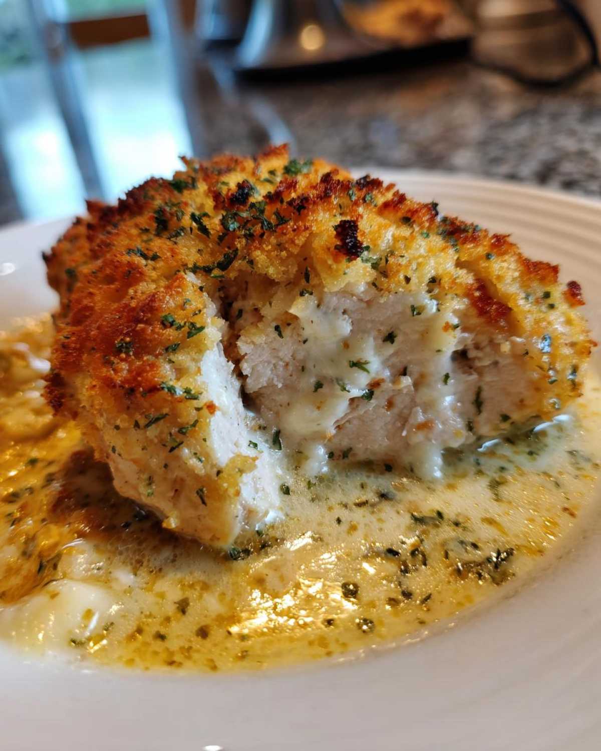 Close-up of a cross-section of Garlic Parmesan Chicken Bake showing crispy crust and melted cheese filling, served in creamy sauce.