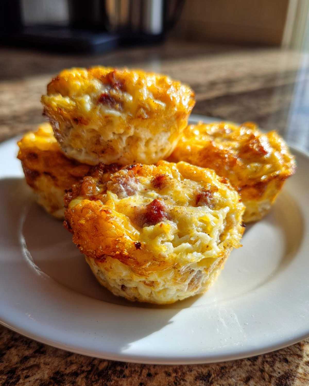 Four golden brown cottage cheese egg cups starbucks style stacked slightly on a white plate.