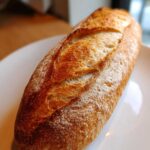 Close-up of a perfectly baked, golden-brown Italian bread loaf with a crisp, scored crust.