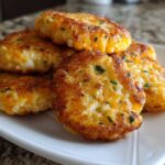 A stack of five golden brown, pan-fried mashed potato cakes mixed with melted cheddar cheese and chives.