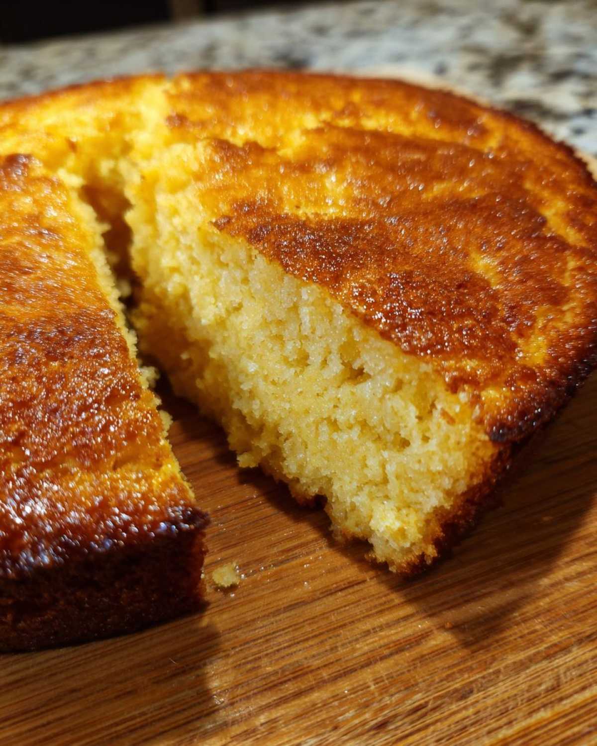 Close-up of golden brown skillet cornbread with a wedge cut out, showing the moist interior texture.