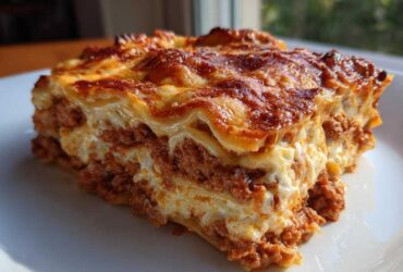 Close-up of a perfectly baked slice of homemade lasagna showing layers of meat sauce and creamy cheese.
