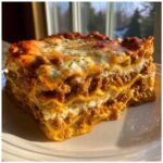 Close-up of a thick, perfectly layered slice of homemade lasagna with rich meat sauce and melted cheese topping.