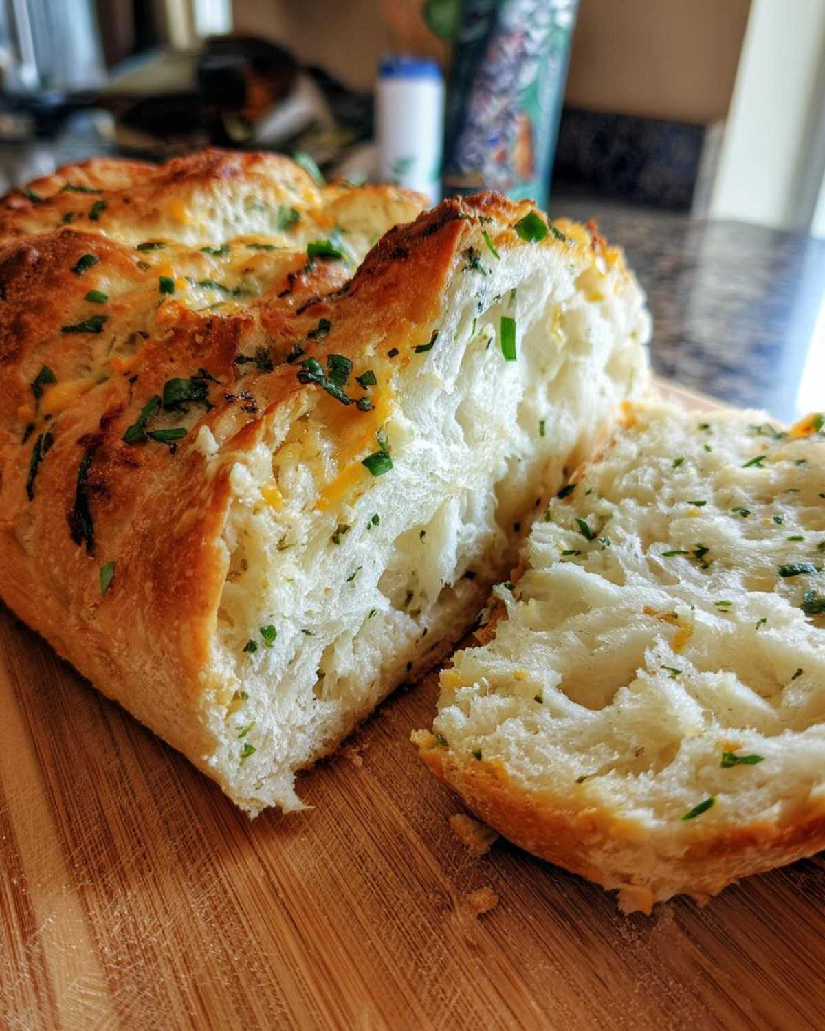 Close-up of freshly baked Italian herb and cheese bread, showing a fluffy interior and cheesy, herby crust.