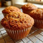 Close-up of four golden brown honey bran muffins cooling on a wire rack after baking.