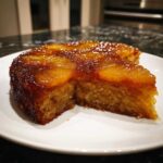 A slice cut from a moist pineapple upside down cake showing caramelized topping and tender crumb.