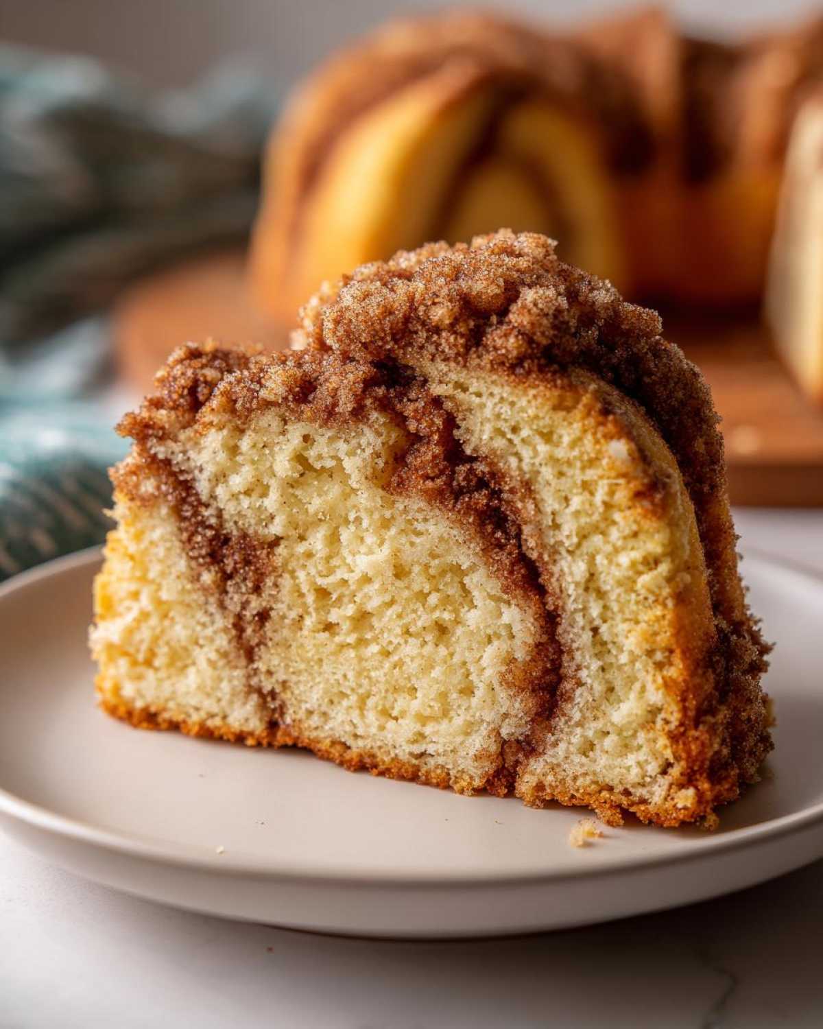 Close-up of a moist slice of sour cream coffee cake featuring a thick cinnamon swirl and generous crumb topping.