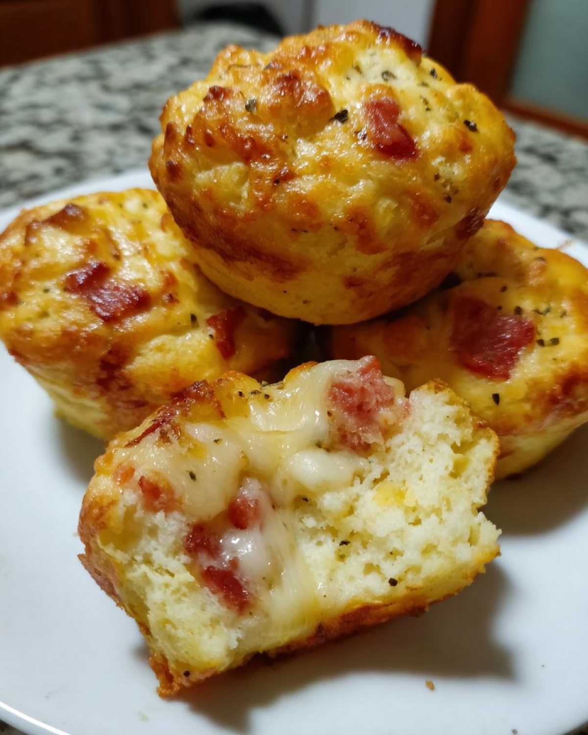 Close-up of pizza muffins, one is broken open revealing gooey melted cheese and pepperoni inside.
