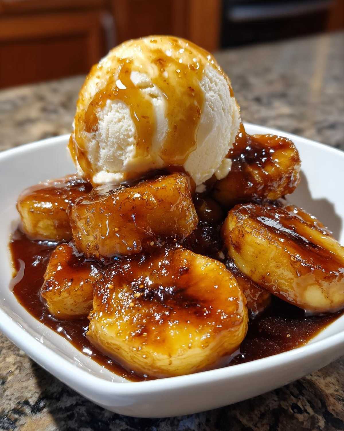 Close-up of caramelized bananas in dark sauce, topped with vanilla ice cream, a perfect Bananas Foster dessert.