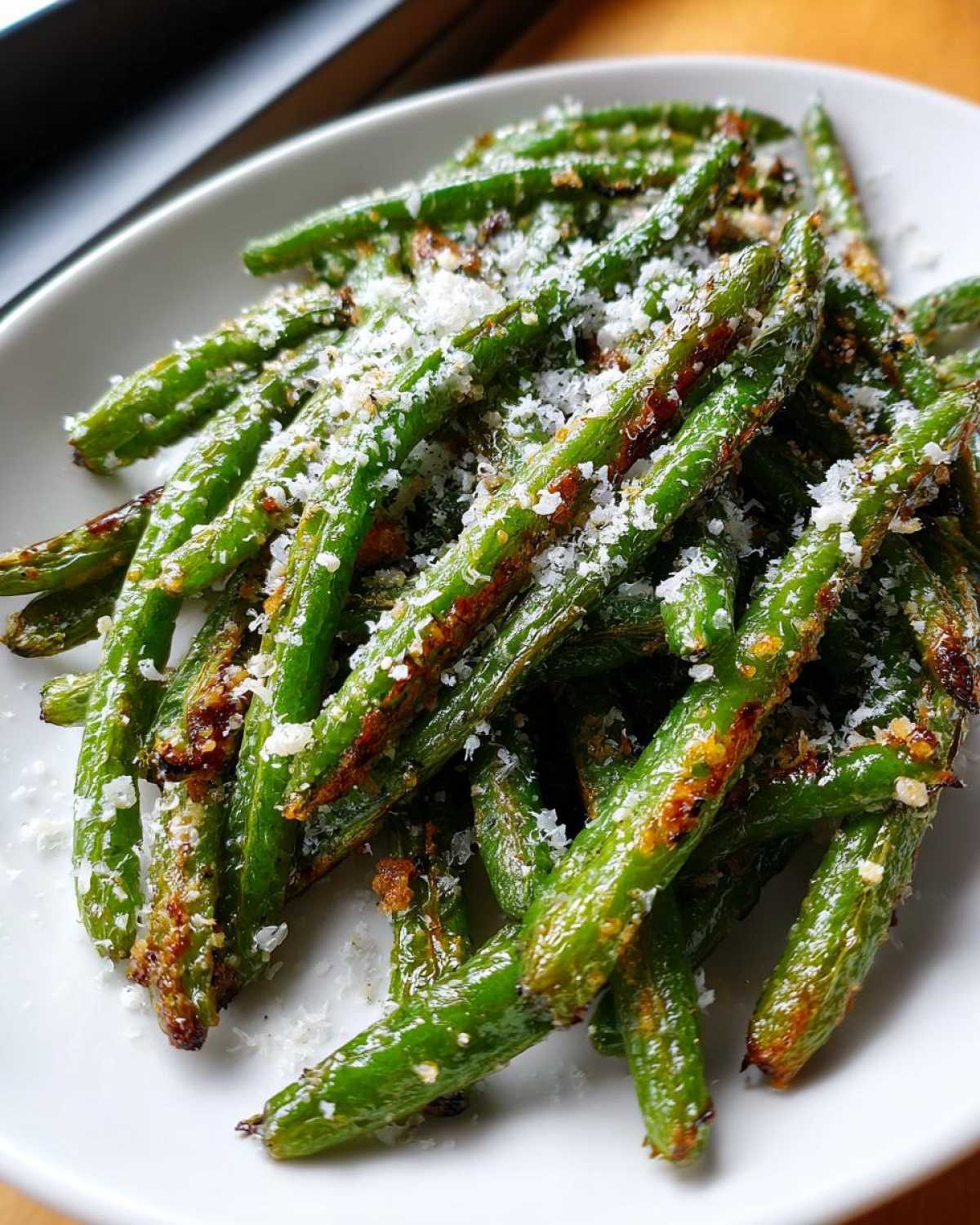 Close-up of roasted green beans topped generously with grated Parmesan cheese.