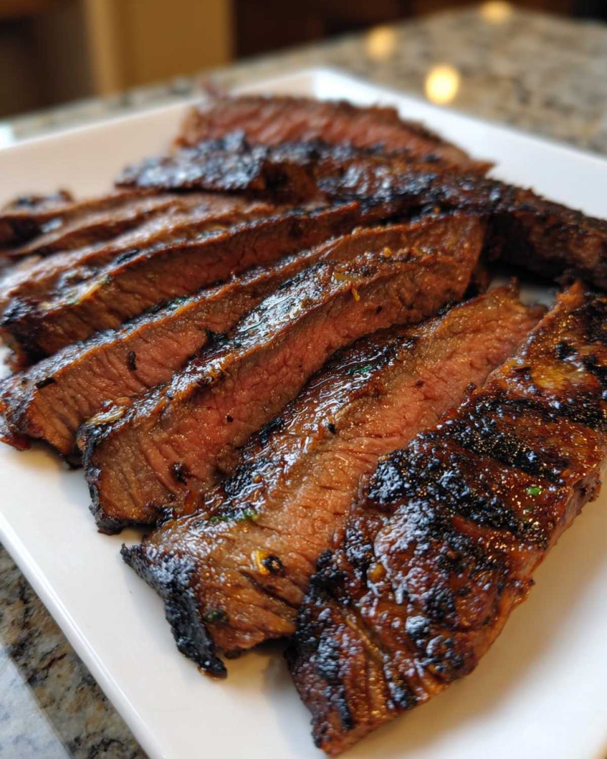 Close-up of medium-rare, grilled, sliced carne asada steak showing char marks and juicy interior.