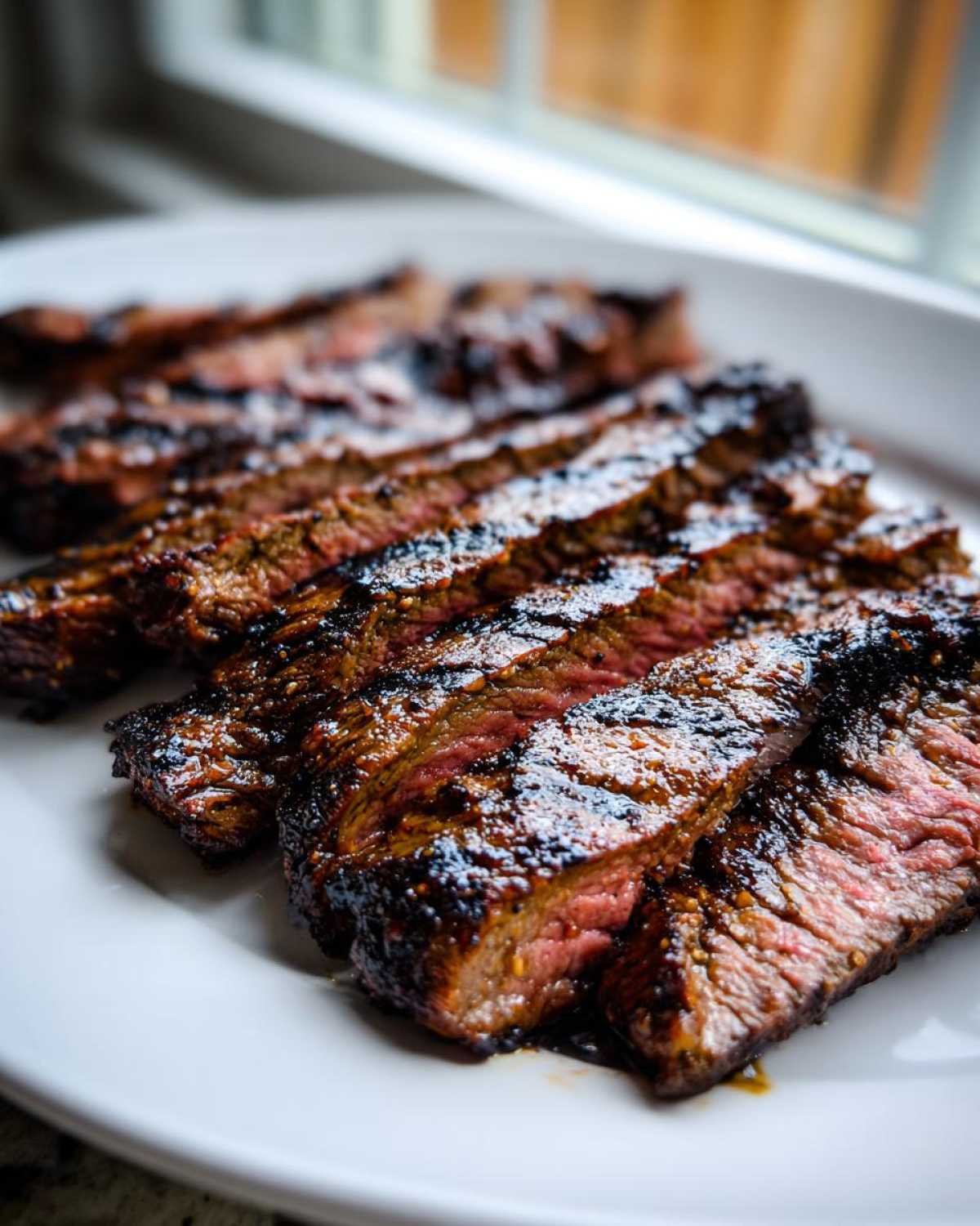 Close-up of perfectly grilled and sliced steak, showing medium-rare interior, prepared with carne asada marinade.
