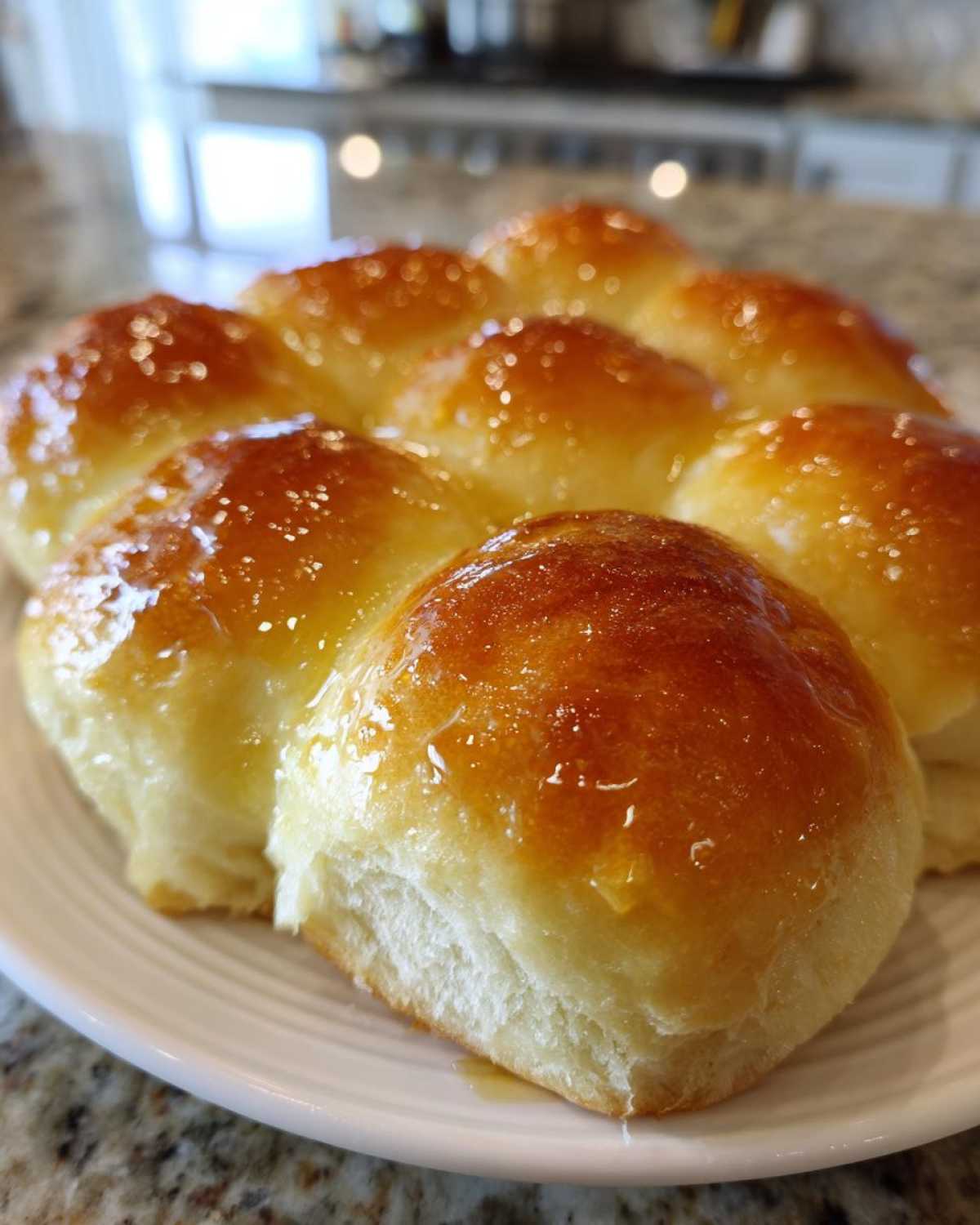 Close-up of freshly baked, soft dinner rolls brushed with a shiny honey glaze.