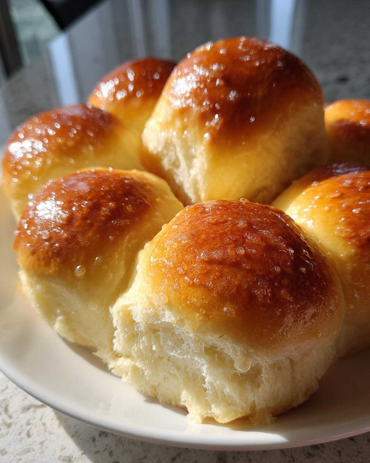 A cluster of freshly baked, soft dinner rolls with a shiny, golden-brown glaze, showcasing their fluffy interior.