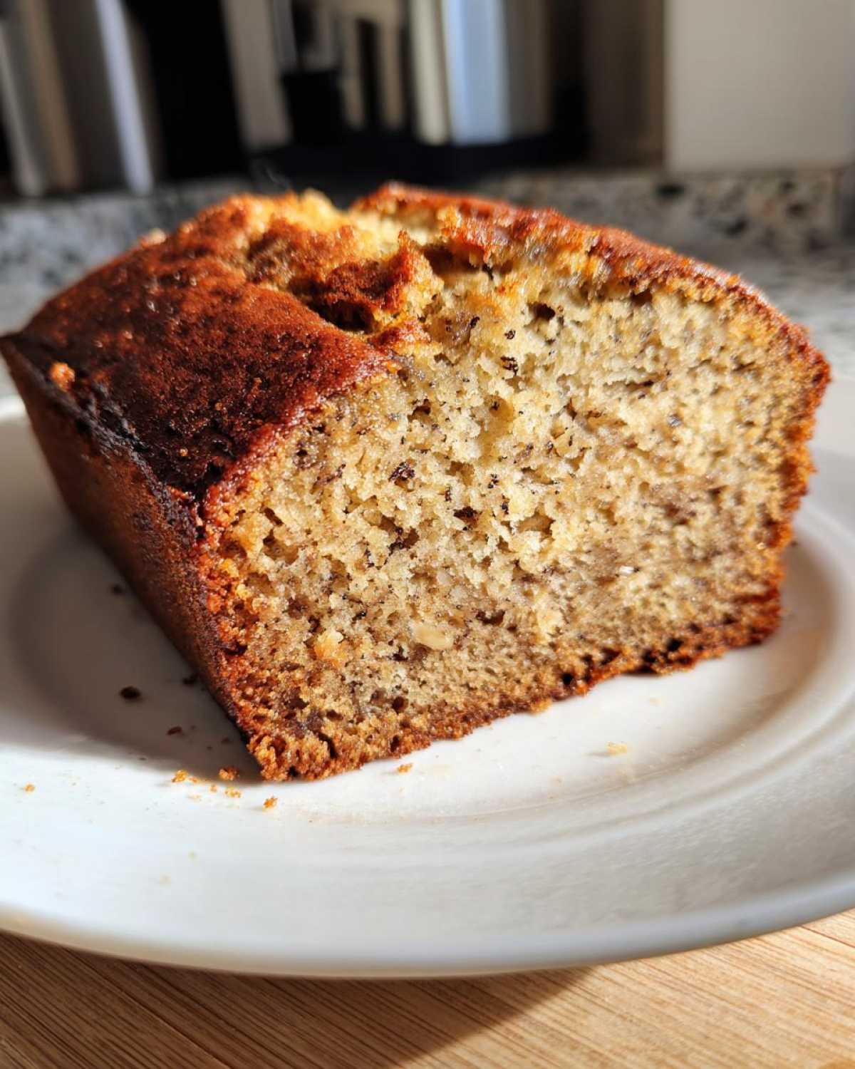 Close-up of a thick slice of moist sugar free banana bread showing its texture and dark, caramelized crust.