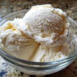 Close-up of three scoops of creamy vanilla protein ice cream served in a clear glass bowl.
