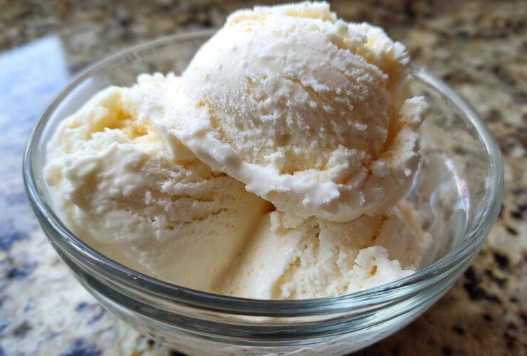 Close-up of three scoops of creamy vanilla protein ice cream served in a clear glass bowl.
