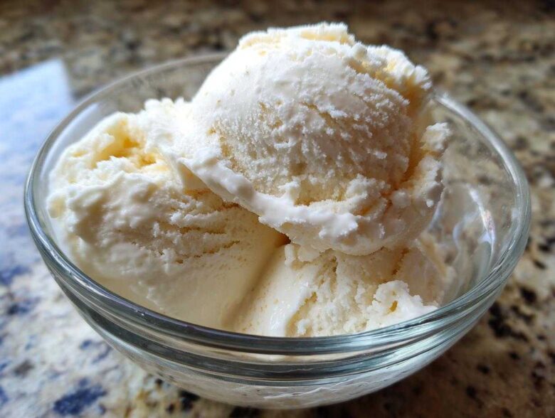 Close-up of three scoops of creamy vanilla protein ice cream served in a clear glass bowl.