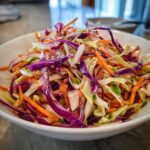 Close-up of a vibrant, colorful cabbage salad featuring shredded red cabbage, green cabbage, and carrots.