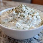 Close-up of thick, creamy 5-Minute Greek Yogurt Ranch Dip topped with dried herbs and spices in a white bowl.