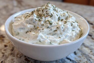 Close-up of thick, creamy 5-Minute Greek Yogurt Ranch Dip topped with dried herbs and spices in a white bowl.