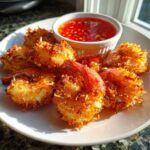 A plate of crispy, golden Air Fryer Coconut Shrimp served with a small bowl of sweet chili dipping sauce.