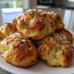 A pile of golden brown Air Fryer Garlic Knots topped with melted butter, fresh parsley, and grated Parmesan cheese.