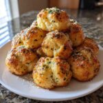 A tempting stack of golden brown Air Fryer Garlic Knots topped with melted butter, grated Parmesan, and fresh parsley.