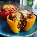 Close-up of a yellow Air Fryer Stuffed Bell Pepper cut open, showing rice and meat filling topped with melted cheese.