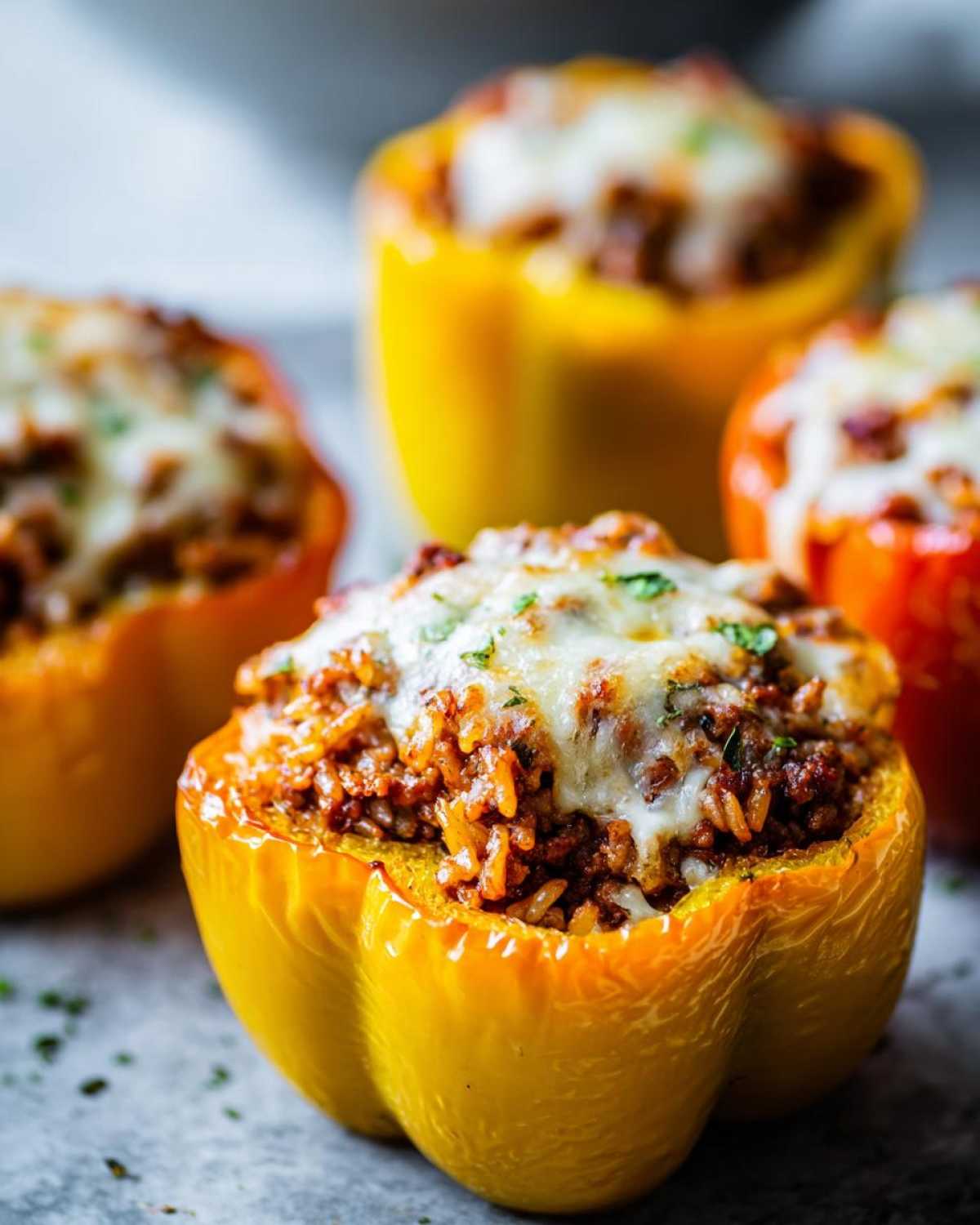 Close-up of a yellow Air Fryer Stuffed Bell Pepper topped with melted cheese and herbs.