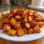 A white plate piled high with golden brown, seasoned Air Fryer Sweet Potato Cubes.