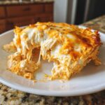 A close-up of a serving of cheesy Baked Buffalo Chicken Dip showing melted cheese pull and shredded chicken.