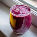 Close-up of a vibrant, thick Blueberry Lemon Chia Smoothie in a clear glass, showing visible chia seeds.