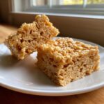 Two squares of chewy Brown Butter Rice Krispie Treat Bars resting on a white plate.