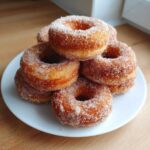 A stack of golden Cinnamon Sugar Air Fryer Donuts heavily coated in sparkling cinnamon sugar on a white plate.