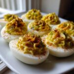A plate of perfectly piped Classic Deviled Eggs with Dill Pickle Relish, dusted with paprika.