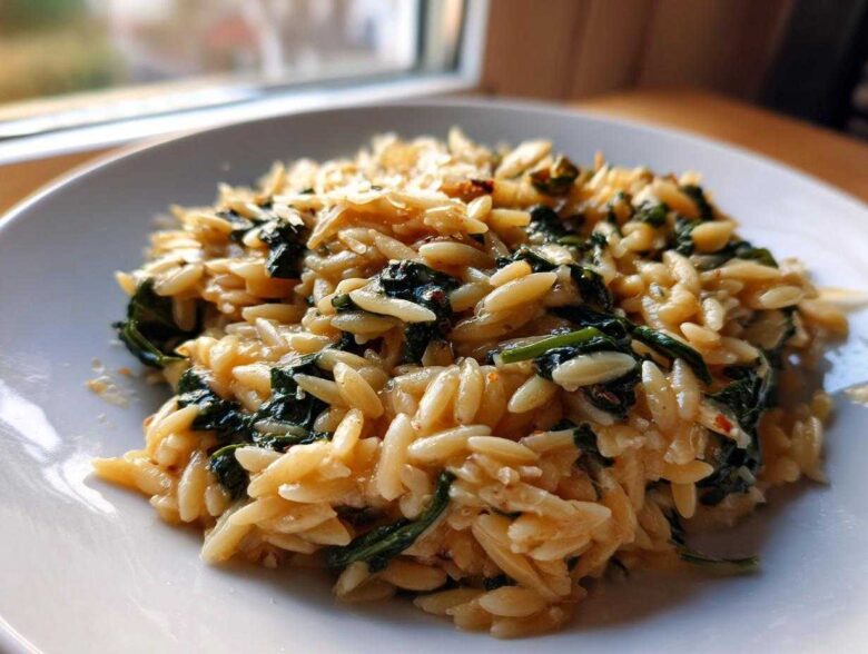 A close-up of a serving of Creamy Garlic Parmesan Orzo with Spinach on a white plate.