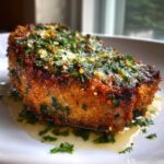 Close-up of a perfectly cooked Crispy Air Fryer Pork Chop smothered in garlic butter and fresh parsley.