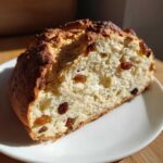 A close-up of a thick slice of Easy Irish Soda Bread with Buttermilk and Raisins, showing a soft crumb and dark raisins.