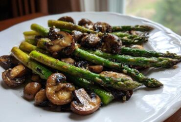 Close-up of vibrant green Garlic Butter Roasted Asparagus and Mushrooms served on a white plate.