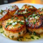 Close-up of perfectly seared Garlic Butter Scallops with Lemon, topped with minced garlic and parsley in butter sauce.