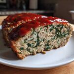Cross-section of a Healthy Turkey Spinach Meatloaf topped with a red glaze, showing visible spinach pieces.