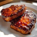Two thick slices of Honey Glazed Ham Steak in the Skillet, glistening with a rich, dark glaze.