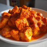 Close-up of tender chicken pieces coated in a vibrant, rich orange sauce, ready for Instant Pot Butter Chicken.